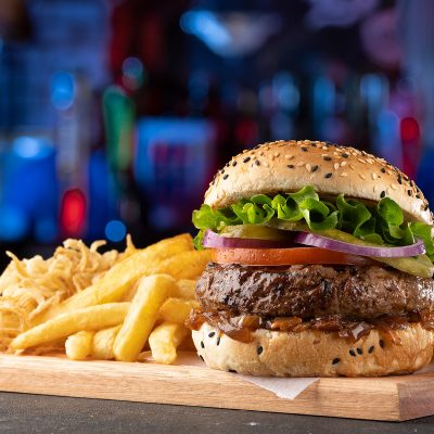 dros beef burger seven with chips and onion rings on wooden board