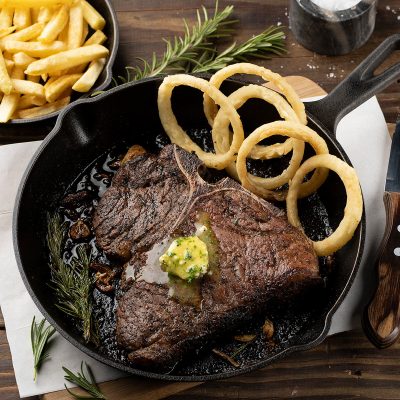 dros T-bone steak with chips and onion rings served in pan