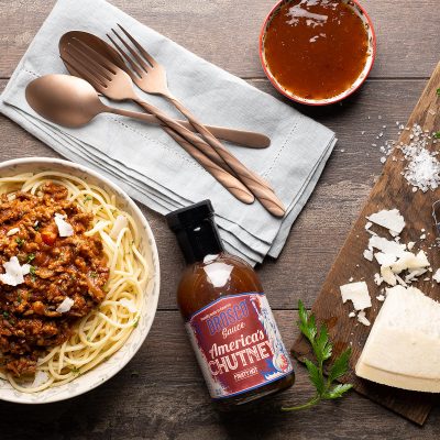 spaghetti bolognese on wooden table setting served with parmesan and sauce