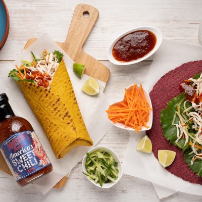Mexican style burrito served on table setting with sauce and condiments