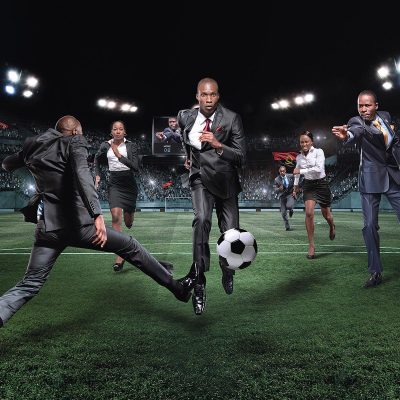 Men in suits playing soccer action shot
