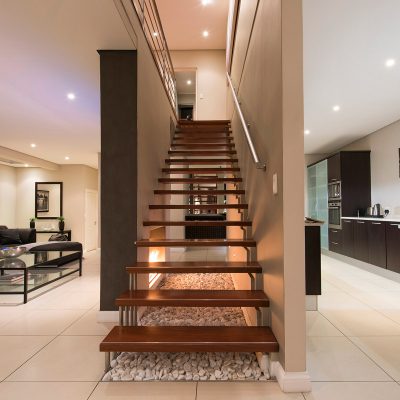 View of modern wooden staircase surrounded by side views of kitchen and living area