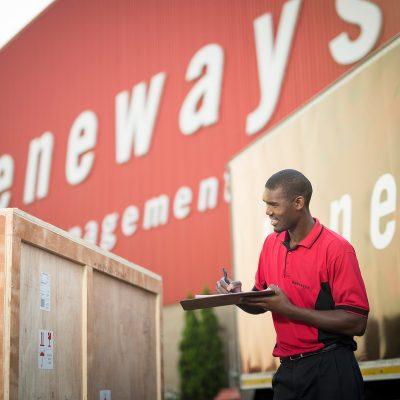 Heneways employee checking clipboard while standing near wooden crate object